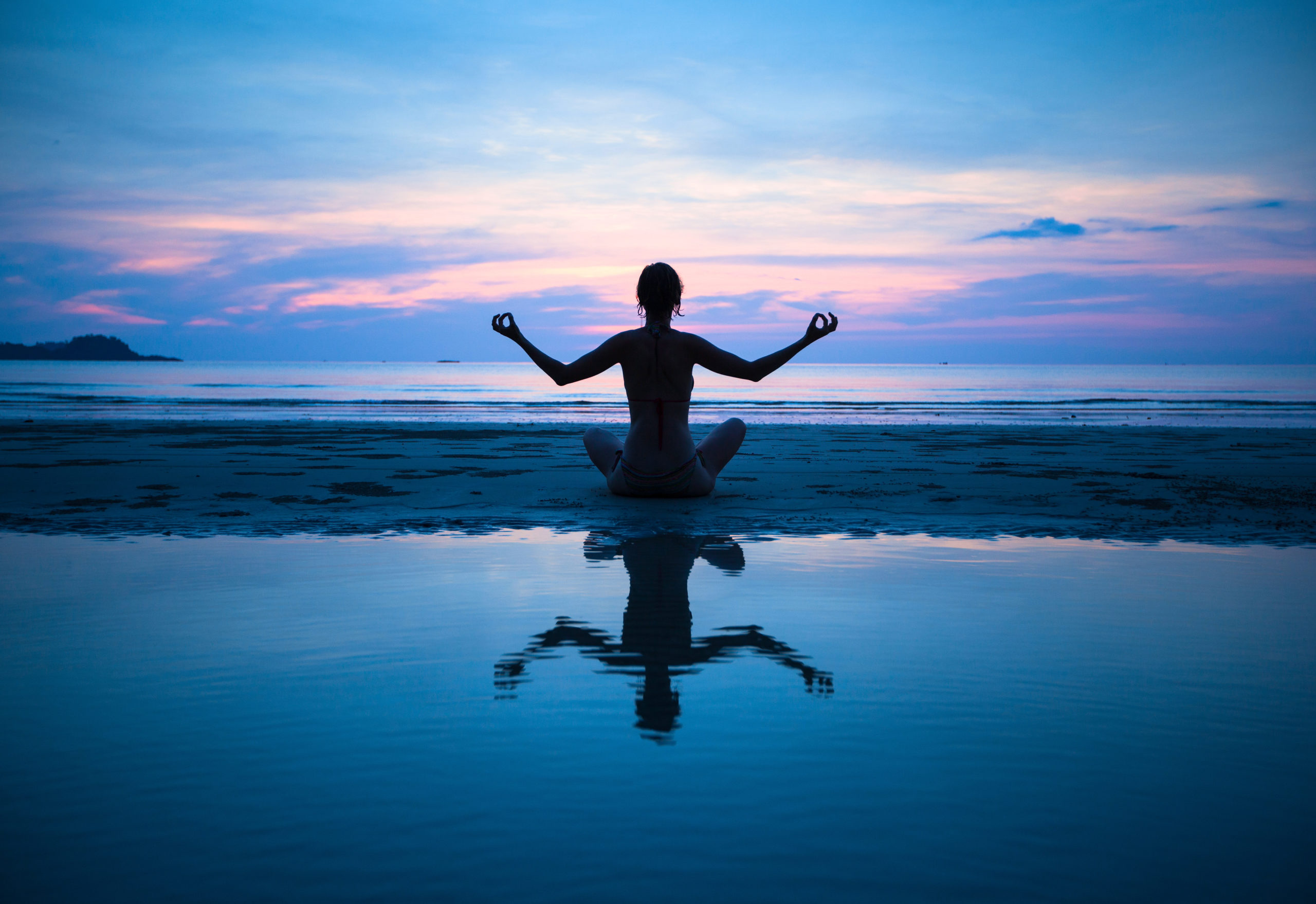 femme pratiquant le yoga au bord de la mer
