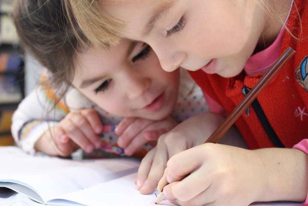 deux enfants écrivant dans un cahier