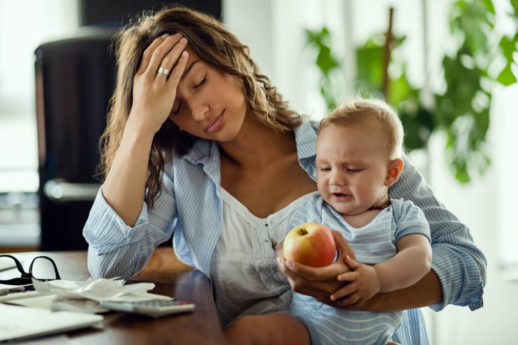 jeune mere se sentant epuisee tout etant son bebe travaillant maison